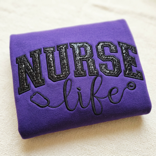 Purple Nurse Life sweatshirt with black glitter lettering and stethoscope embroidery detail